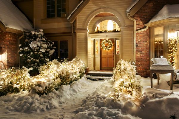 چراغ‌های کریسمس بیرون مسیر را به سمت درب ورودی در یک عصر برفی خط می‌کشند