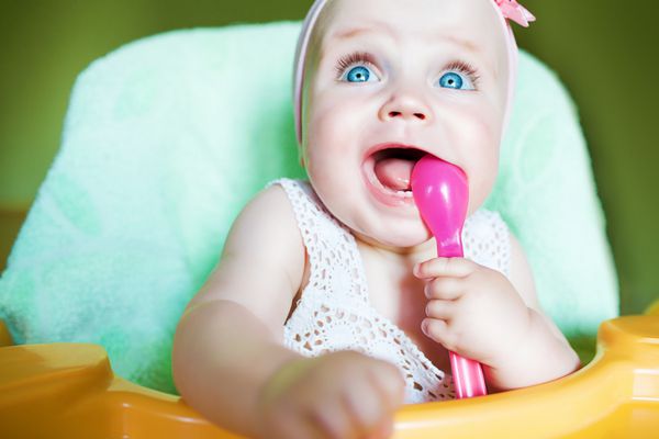 کودک کوچک با قاشق صورتی در دهان