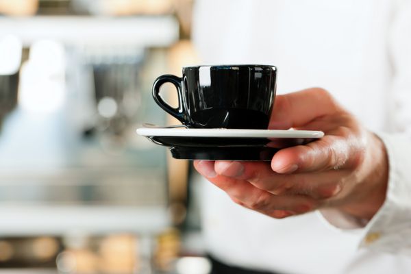 کافی شاپ - ایستا قهوه یا کاپوچینو را ارائه می دهد نمای نزدیک روی لیوان