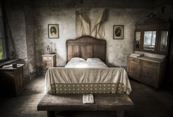 مناظر اتاق خواب خزنده دیوارهای ترک خورده و کف چوبی همراه با فضای مذهبی