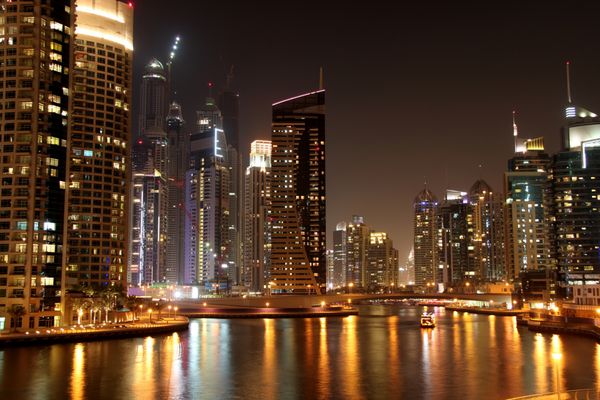 نمای زیبا از شهر دبی در شب با قایق امارات متحده عربی روشن شده است