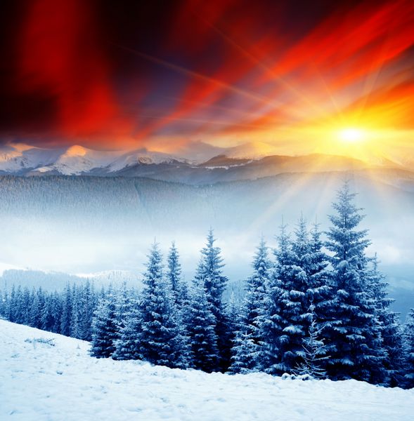 غروب باشکوه خورشید در چشم انداز کوه های زمستانی آسمان دراماتیک