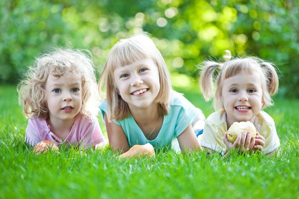کودکان شادی که روی چمن دراز کشیده اند پیک نیک خانوادگی در پارک بهار