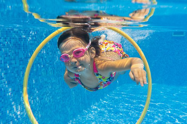 کودک زیر آب خندان شاد در استخر شنا دختر بچه شنا می کند ورزش بچه ها