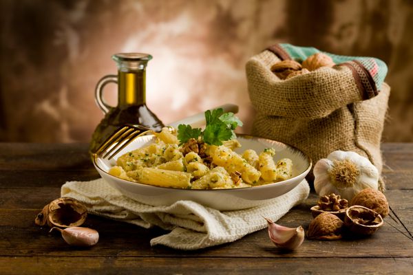 غذای منطقه ای ایتالیایی ساخته شده از پاستا با پستو گردو روی میز چوبی