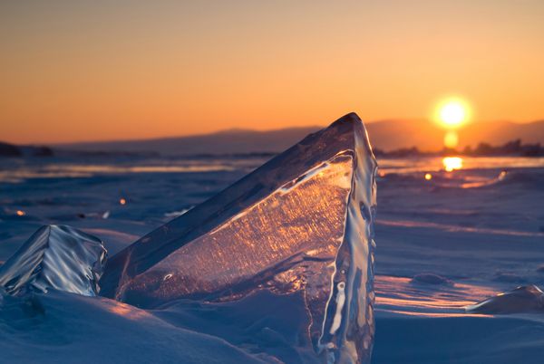 هوموک یخی با فلاش نور در یخ دریاچه بایکال در غروب آفتاب