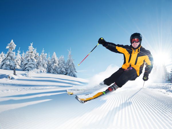 اسکی باز در کوهستان پیست آماده و روز آفتابی