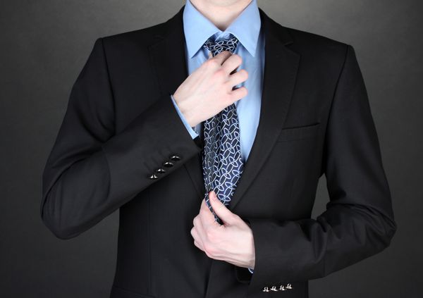 تاجر در حال تصحیح کراوات در پس زمینه سیاه