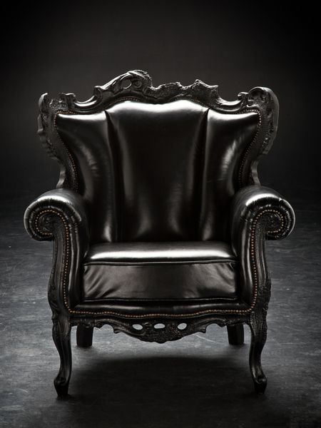 صندلی مشکی قدیمی روکش چرمی جدا شده بر روی پس‌زمینه مشکی خراش