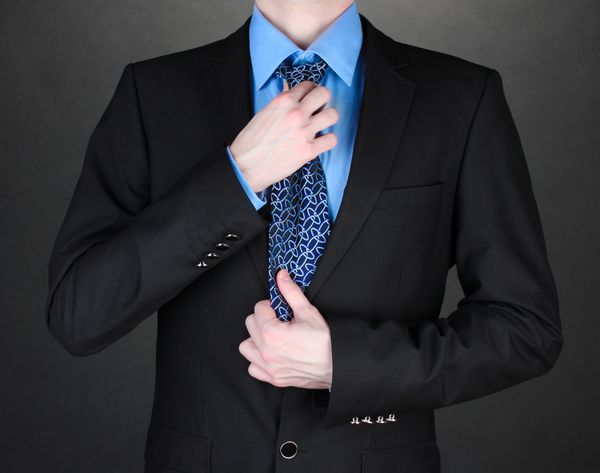 تاجر در حال تصحیح کراوات در پس زمینه سیاه