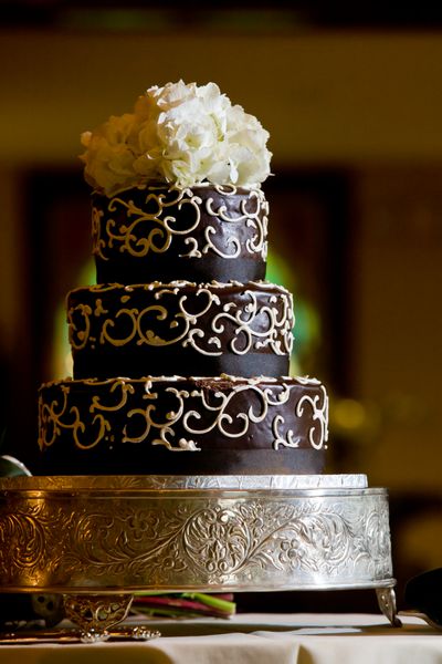 کیک عروسی شکلاتی با جزئیات مات سفید و گل در بالا