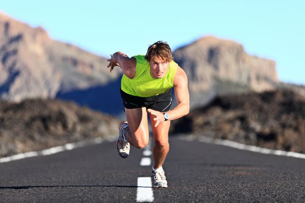 دونده سرعت مردی که در جاده با سرعت زیاد در منظره کوهستانی عجیب و غریب می دود دونده ورزشکار مرد در دوی سرعت شدید در طول تمرین در فضای باز