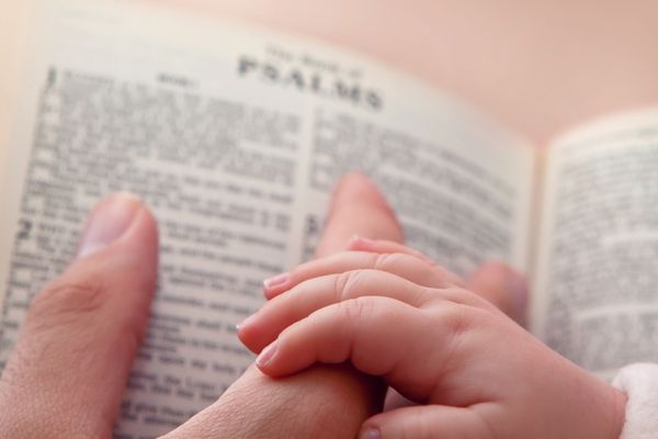 کودکی که انگشت پدر را در آغوش می گیرد در حالی که به آیه مزامیر اشاره می کند