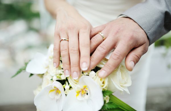 دست عروس و داماد با حلقه ازدواج روی دسته گل عروسی