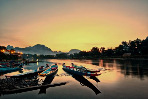 قایق های دم بلند در غروب خورشید در رودخانه آهنگ وانگ وینگ لائوس