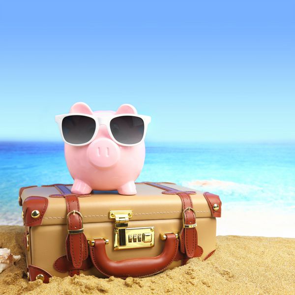 چمدان با قلک با عینک آفتابی در ساحل استوایی