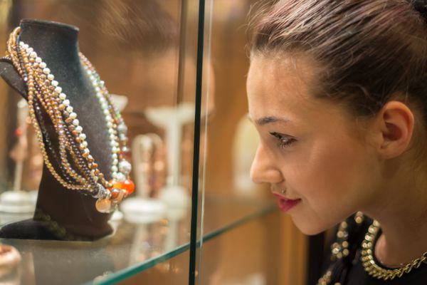 زن جوانی که به ویترین جواهر فروشی نگاه می کند