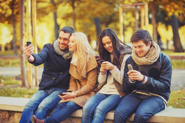 تابستان تعطیلات تعطیلات مفهوم افراد شاد - گروهی از دوستان یا زوج ها با گوشی هوشمند در حال تفریح در پارک پاییز