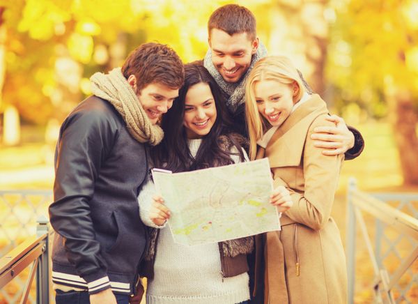 مفهوم تعطیلات و گردشگری - گروهی از دوستان یا زوج ها با نقشه گردشگری در پارک پاییز