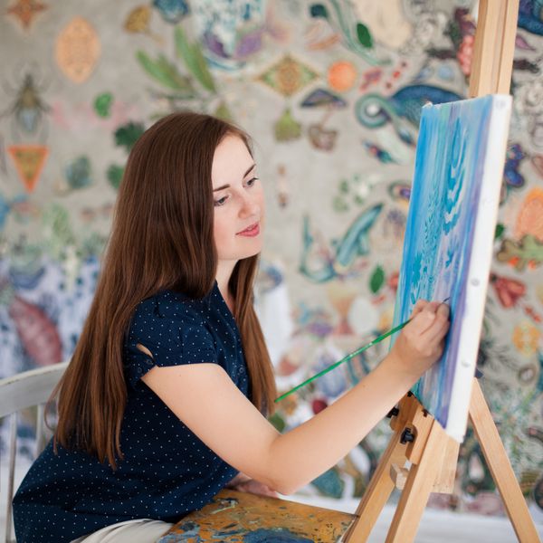 زن جوان در استودیوی خود روی بوم نقاشی می کند