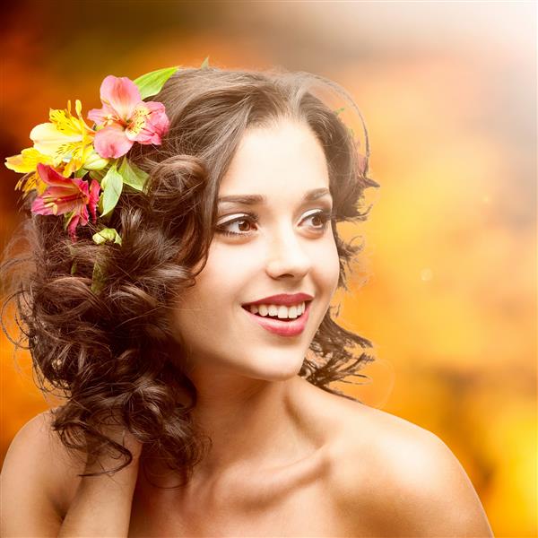 زن جوان زیبا با گل هایی در مو در پس زمینه پاییزی