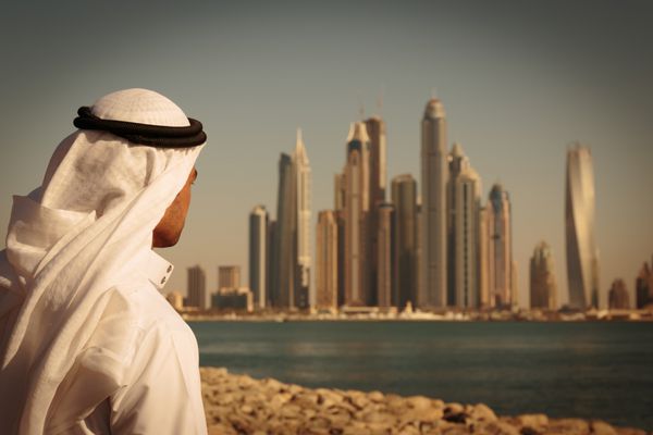 دبی امارات - 7 نوامبر ساختمان های مدرن در دبی مارینا امارات متحده عربی در شهر کانال مصنوعی به طول 3 کیلومتر در امتداد خلیج فارس مردی با لباس عربی به شهر نگاه می کند پررنگ