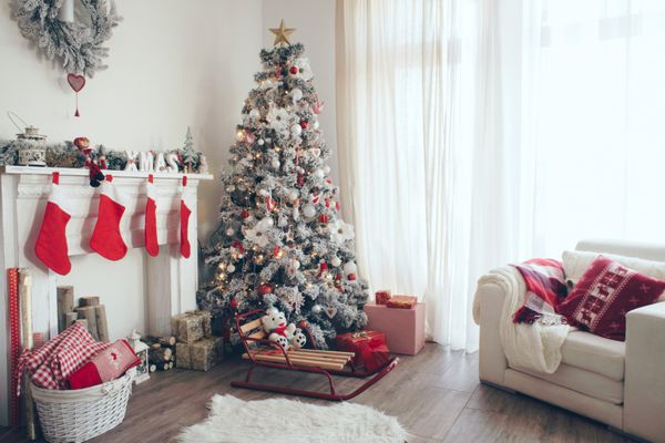 اتاق زیبای تزئین شده با درخت کریسمس با هدایایی زیر آن