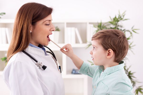 کودک کوچک با پزشک در حال معاینه در مطب