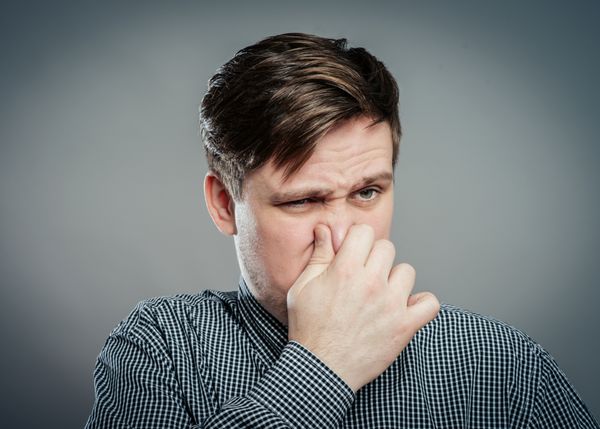مردی که بینی خود را در برابر بوی بد گرفته است