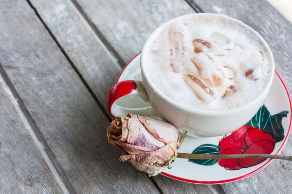 چای شیر سرد در فنجان قهوه روی میز چوبی در تابستان