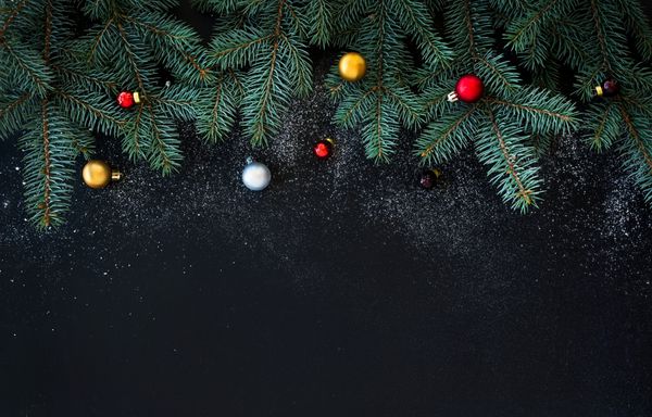پس‌زمینه دکوراسیون کریسمس یا سال نو شاخه‌های خزدار توپ‌های شیشه‌ای رنگارنگ روی پس‌زمینه گرانج مشکی با کپی sp