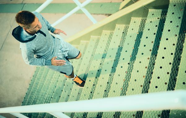 مرد دونده دویدن روی پله ها در شهر تمرین ورزشی ورزشکار مرد جوان دویدن در حال تمرین و انجام تمرین در فضای باز در شهر تناسب اندام و ورزش در فضای باز محیط شهری