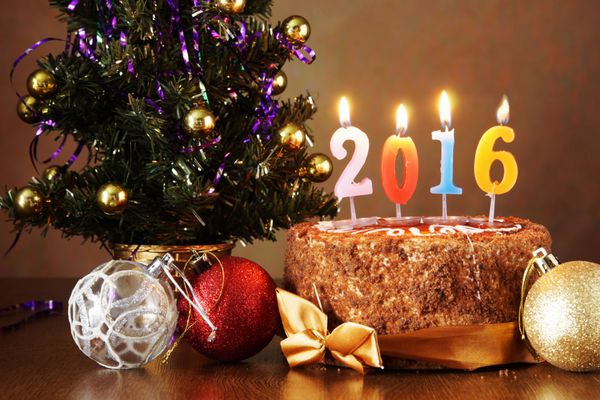سال جدید 2016 طبیعت بی جان کیک شکلاتی و درخت صنوبر مصنوعی با شمع های سوزان در پس زمینه قهوه ای