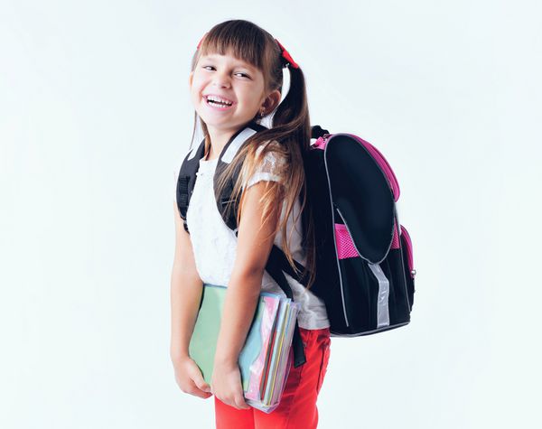 پرتره دختر نوجوان با کوله پشتی مدرسه که پوشه های رنگی جدا شده در پس زمینه سفید را در دست دارد