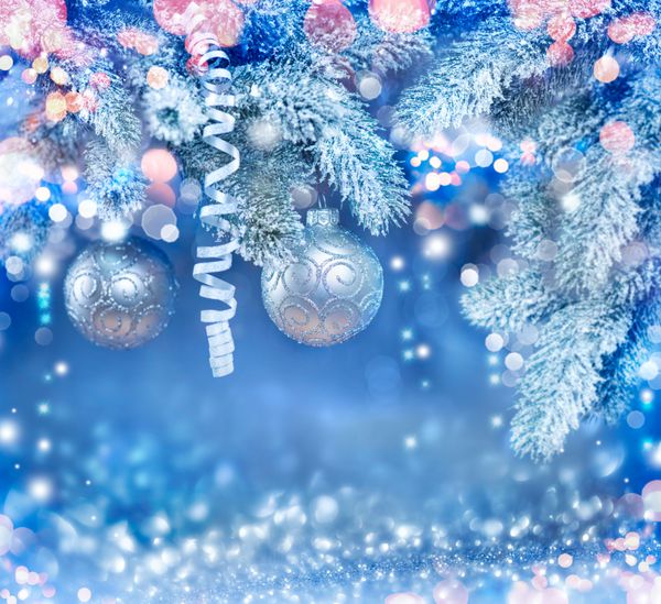 پس‌زمینه تعطیلات کریسمس چوب‌های آویزان روی درخت کریسمس پس‌زمینه سال نو با برف تزیین بوکه آبی تار انتزاعی گلدسته چشمک زن درخت کریسمس تزئین شده چراغ ها چشمک می زنند