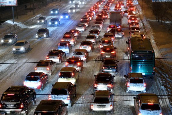 نووسیبیرسک روسیه - 21 ژانویه 2015 ترافیک ماشین در مرکز شهر در یک عصر زمستانی این شهر در 70 سال به نقطه عطف 1 میلیون نفر جمعیت رسید و یکی از اولین ها در جهان است