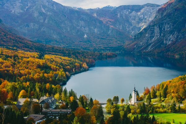 نمایی خیره کننده از دریاچه معروف بوهینج از بالا منظره زیبا از کوه های تریگلاو پارک ملی تریگلاو و کلیسای سنت جان باپتیست اسلوونی اروپا