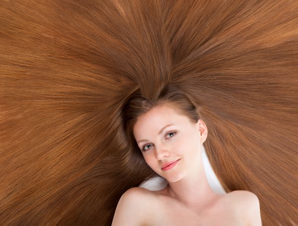 پرتره نزدیک از زن جوان زیبا با موهای براق بلند ظریف که روی زمین خوابیده است مفهوم مدل موی دخترانه مراقبت از موهای سالم قهوه ای خالص