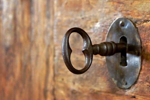 نمای نزدیک از یک سوراخ کلید قدیمی با کلید در یک در چوبی عتیقه