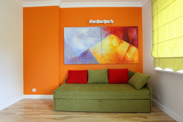 دیوار نارنجی و مبل سبز در اتاق نوجوان