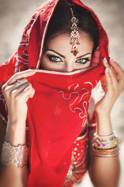 زن جوان هندی زیبا با لباس سنتی با آرایش عروس و جواهرات عروس زیبا که به طور سنتی در خارج از منزل در هند لباس می پوشد دختر بالیوود در ساری شکم عربی