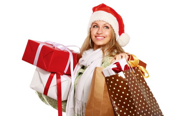 زن جوان با کلاه بابا نوئل که کیسه های خرید را در دست دارد جدا شده در پس زمینه سفید