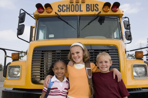پرتره دوستان شادی که جلوی اتوبوس مدرسه ایستاده اند
