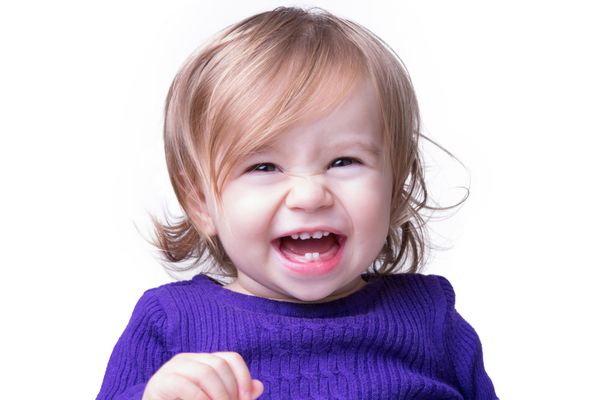 نوزاد شاد و ناز با دندان های تازه اش بی باک و آزادانه می خندد و به دوربین نگاه می کند جدا شده روی سفید