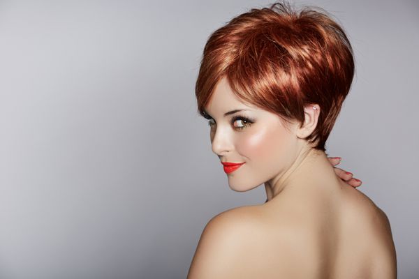 زن جوان زیبا با موهای قرمز با مدل موهای کوتاه پیکسی در پس زمینه استودیو
