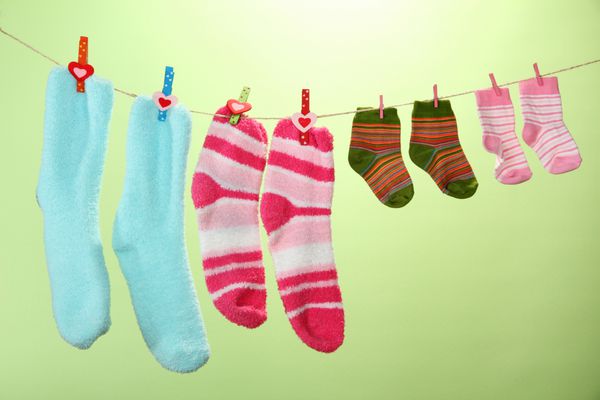 جوراب های رنگارنگ آویزان به بند رخت در زمینه رنگی