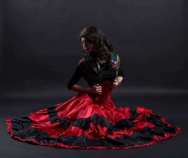زن جوان با لباس های سنتی اسپانیایی دراز کشیده است