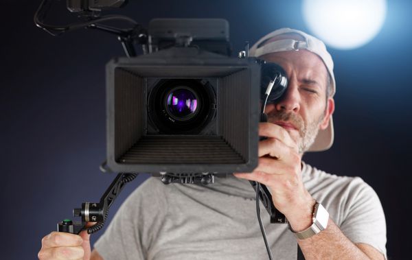 اپراتور دوربین که با دوربین سینما روی شانه خود کار می کند