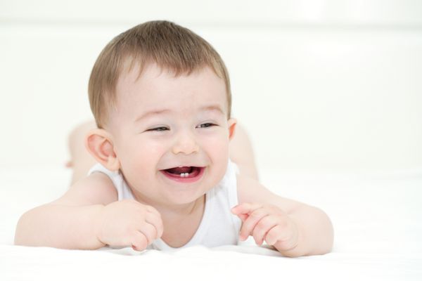 پسر بچه ای که لبخند می زند و اولین دندان هایش را نشان می دهد در داخل خانه با copy sp نزدیک کنید
