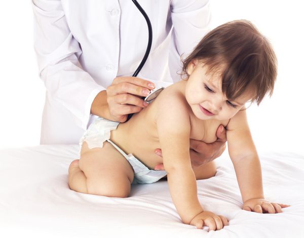 پزشک زن جوان در حال چک کردن نوزاد با گوشی پزشکی در زمینه سفید